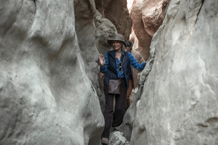 Two people hiking through a narrow rocky canyon.