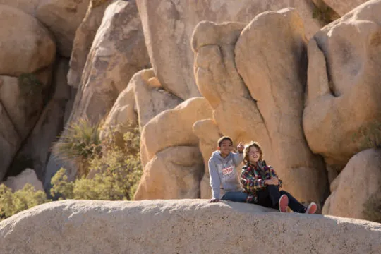a group of people standing in front of a large rock