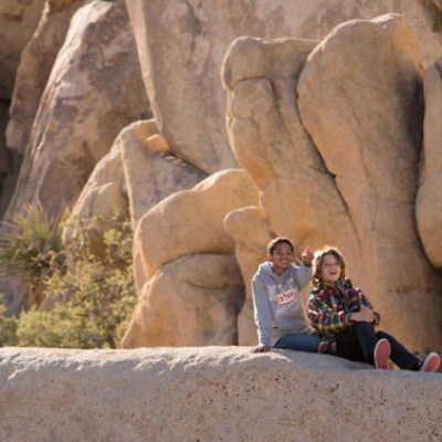 a group of people standing in front of a large rock
