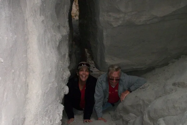 a man and a woman standing next to a stone wall